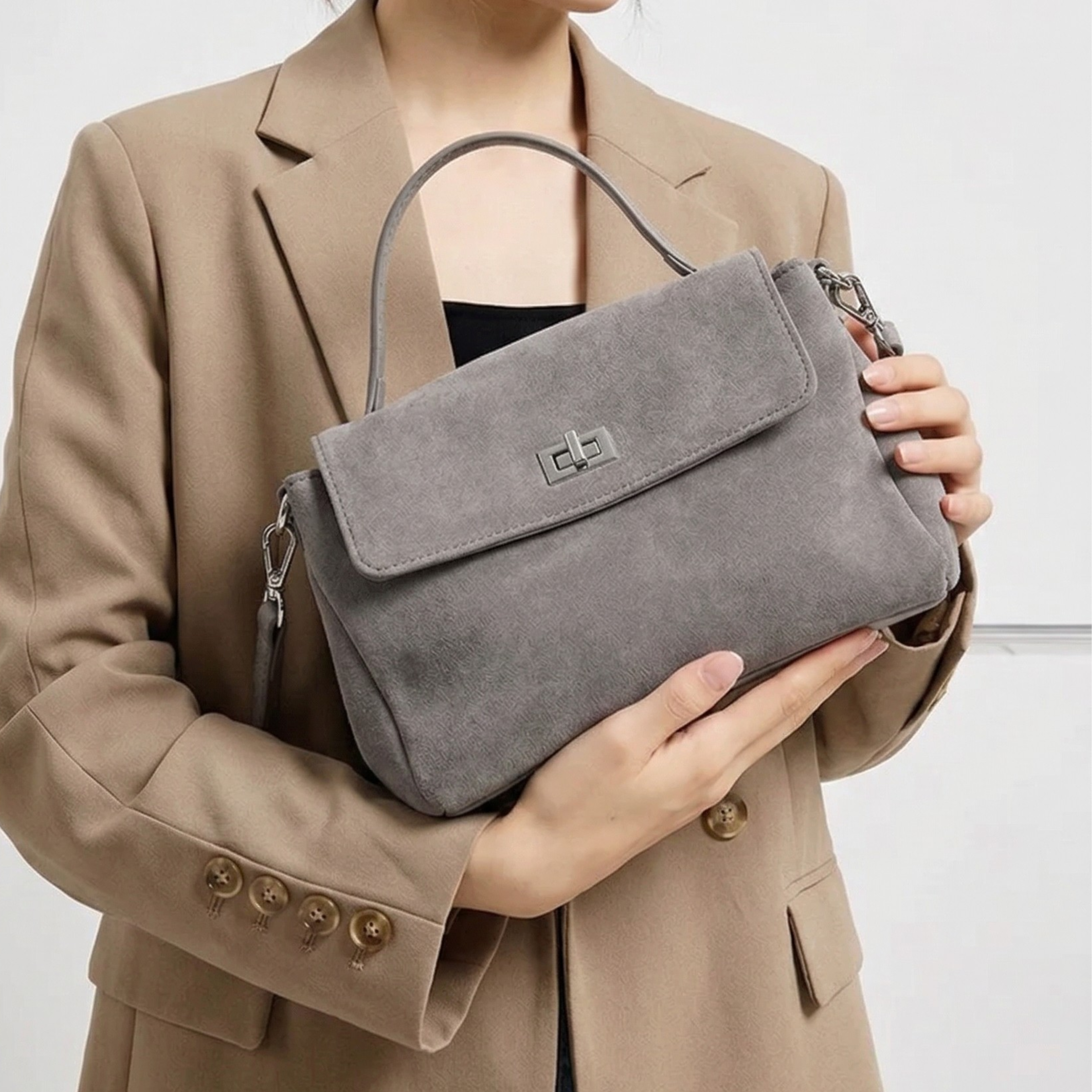 Person holding a gray handbag against a neutral background